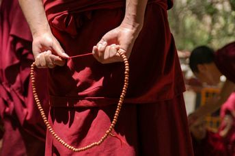 Tibetan Buddhist Monk with his red robe and prayer beads.