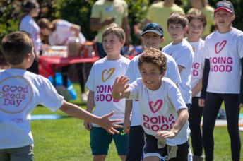 Children wearing “Doing Good” shirts run and play together at a community event.