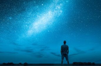 A person stargazes at a night sky.