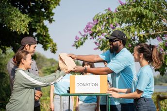 A team of volunteers with a donation box outdoors.