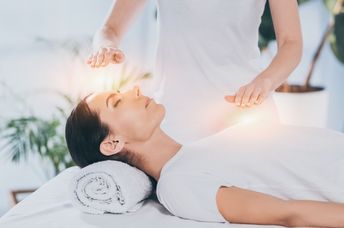 A calm woman receives reiki healing therapy.