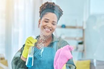 A smiling woman cleans a hospital window.