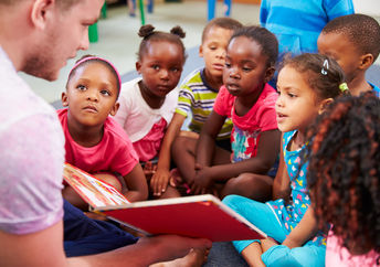 A volunteer reads a book to children. (Shutterstock)