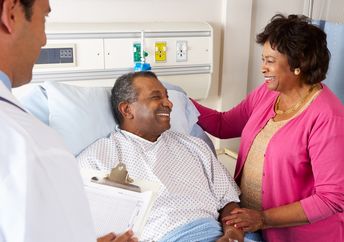 Doctor Talking To Senior Couple On Ward