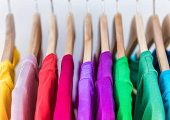 Shirts in different colors hang in a closet.
