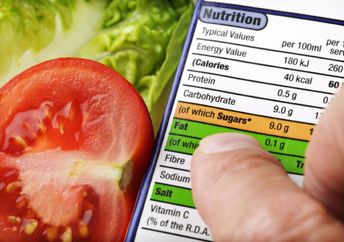 Reading a nutrition label on food packaging with fresh salad background