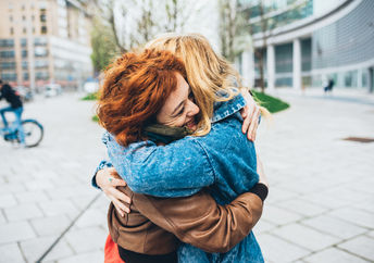 Two friends meeting in the street of the city and hugging
