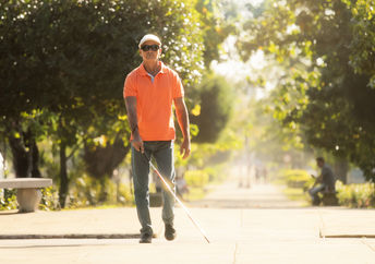 Visually impaired man with walking stick, crossing the street