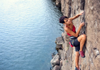 take a risk - Female climber dangles from the edge of a challenging cliff