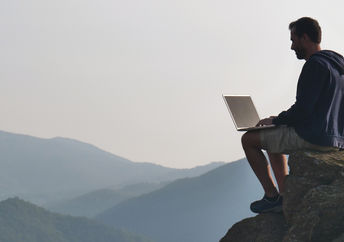 man working outdoors on laptop