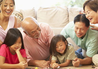 A family laughs while playing a board game.