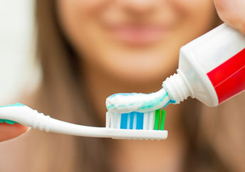 Woman putting toothpaste on a toothbrush.