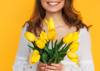 Photo of happy woman holding flowers to illustrate kindness