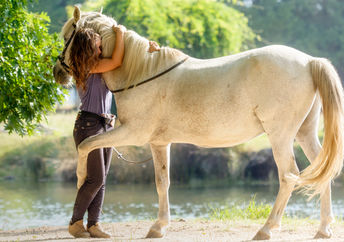 A woman is hugging a retired racehorse.