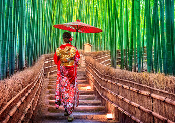 A Japanese woman in kimono enjoys exercise as she walks through a bamboo forest.