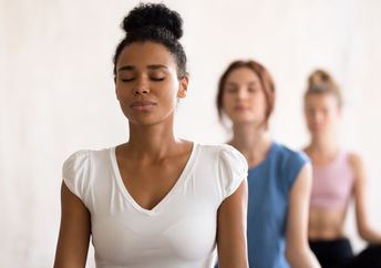 Women of diverse backgrounds meditate together.