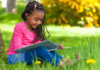 Young girl reading a book outside.
