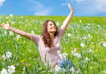 Happy woman sitting in a field of daffodils.