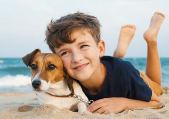 Happy boy hugging his Jack Russell terrier at the seashore