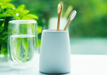 Bamboo toothbrushes in a cup and glass with water