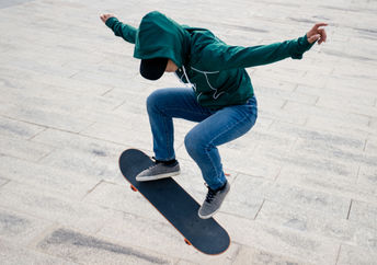 An Asian skateboarder jumps in the air.