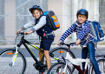 Two boys riding bicycles to school.