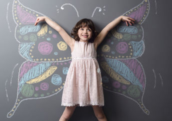 Little girl with a chalked butterfly behind her, a symbol of positive change and creativity.