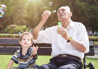 A young boy and an old man blowing bubbles.