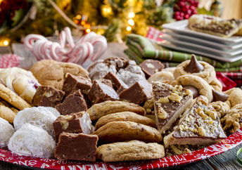 A plate of holiday treats in front of a Christmas tree.
