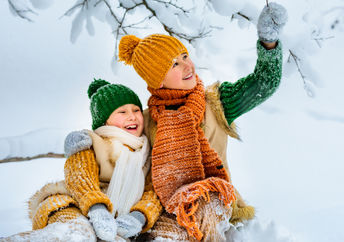 Two young girls happily play in the snow.