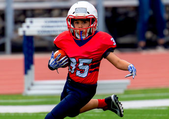 Young athletic boy playing in a youth tackle football game