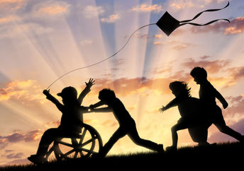 Happy boy in wheelchair playing with children and kite.