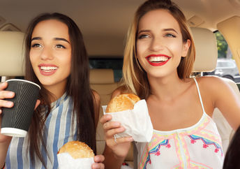 Young women eating fast food in a car.