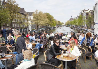 People enjoy a gezellig life sitting in an outdoor cafe Amsterdam.