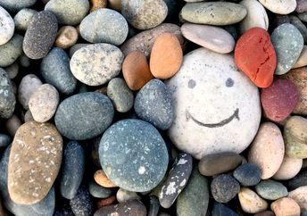 Stone with a painted smile to illustrate kindness.