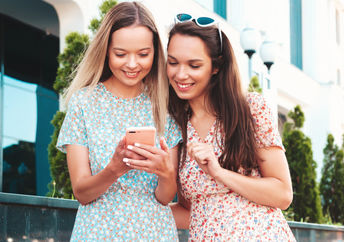 Two girls use a smartphone.