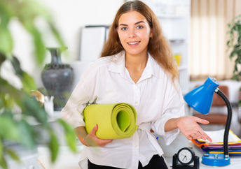Happy young office worker with yoga mat.