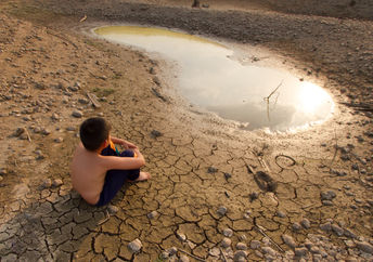 A child sitting near by a water source.