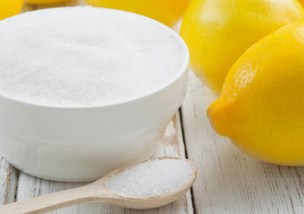 A bowl of citric acid beside lemons.