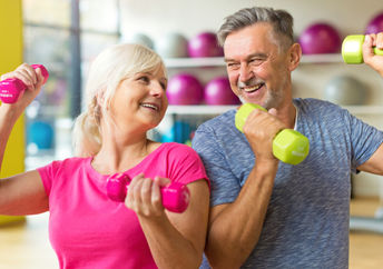 A mature couple lifts weights together, a workout for the body and mind.