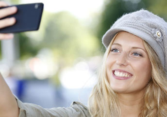 A young woman smiles as she poses for a selfie.
