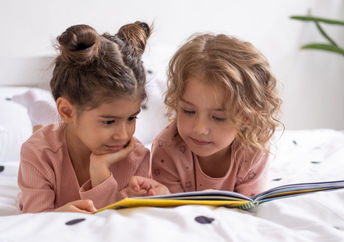 Two sisters reading a book before bedtime.
