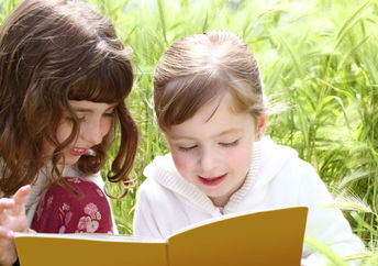 Two girls reading a book they found in a park.