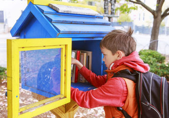 Child taking a book from a little street library.