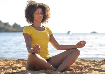 Doing yoga on a beach.