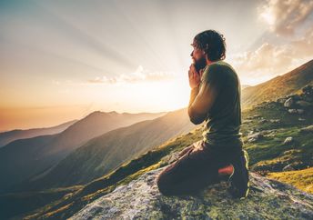 A man sits at sunset in the mountains.