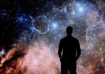 A young man standing in front of a huge image of space.