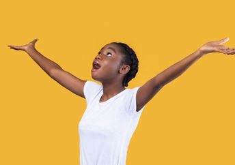 An amazed woman looks up with her hands raised.