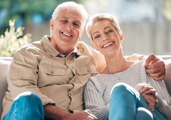A senior couple sits on a couch.