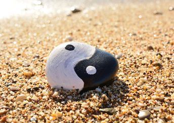 Yin and Yang painted on a rock by the sea.